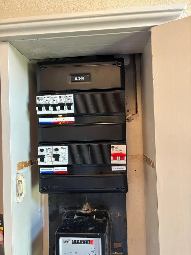 Geplaatste Eaton-groepenkast met vijf EMAT-automaten, twee aardlekschakelaars en een rode hoofdschakelaar, met afdekking en labels